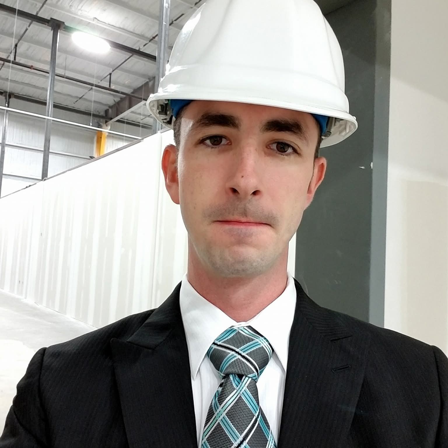 Gary wearing a hard hat and suit inside an industrial building
