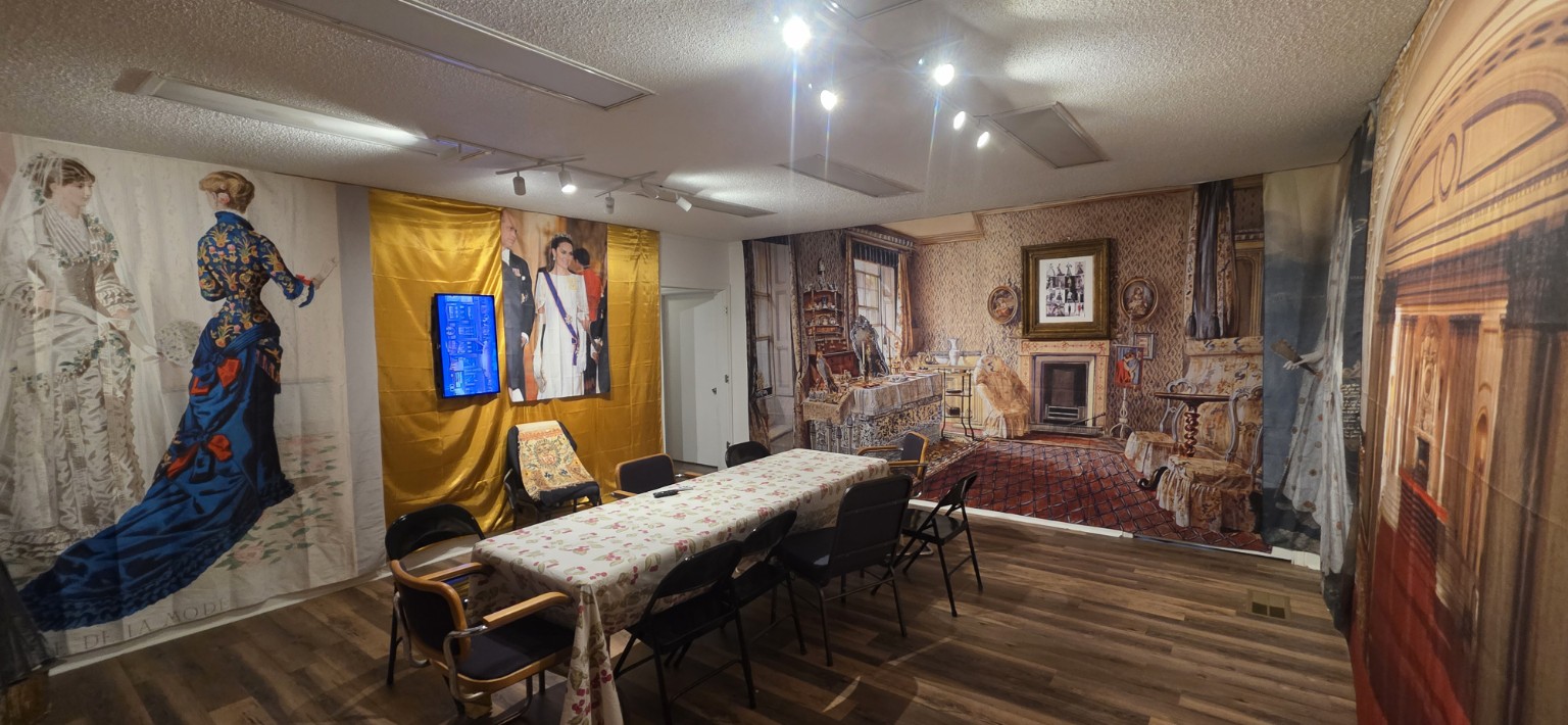 A gallery room with a long table, historical photographic backdrops and an exhibit screen
