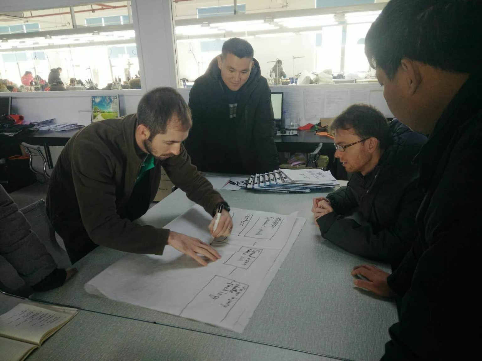 A group collaborating over plans spread across a table